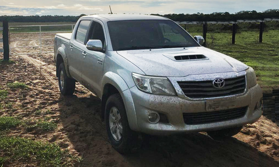 carro offroad Toyota Hilux entrando em uma fazenda com estrada de terra
